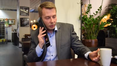 Barnombudsman Tuomas Kurttila på kafé, ringer med mobiltelefon