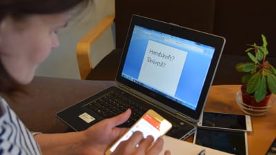 Silja skriver på mobilen framför datorn.