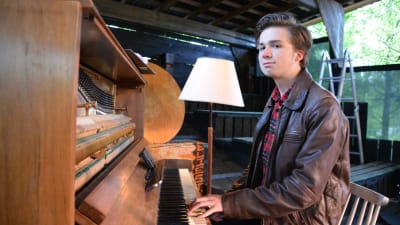 Arthur Eriksson framför pianot på Postbacken sommaren 2017. Han står för musiken i pjäsen Hotelliggaren.