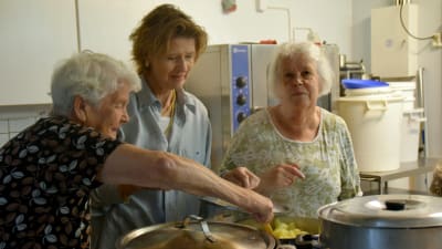 Ella Engberg, Loa Droz och Else-Maj Bäckström står i ett kök och rör i en kastrull med potatis.