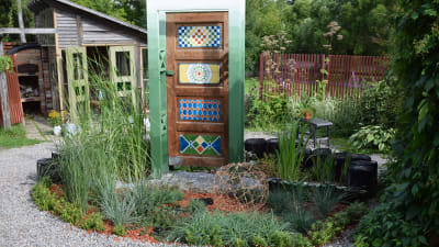 Grästrädgård med färggrannt målad dörr som portal i mitten