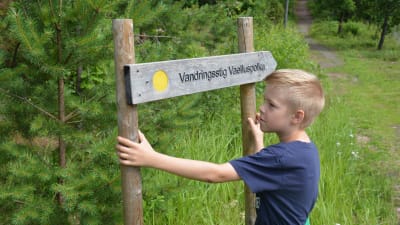 Linus Forssell håller i skylt med texten vandringsstig.
