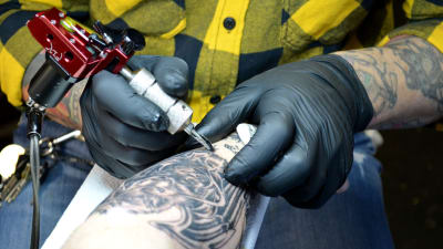 Dag Bäcklund använder tatueringsmaskin.