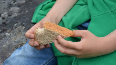 Pojke håller en smörgås i handen.
