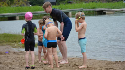 Simskolelärare Anton Ristimäki uppmuntrar barnen att våga sig i vattnet.
