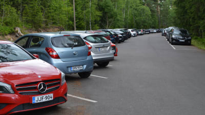 Rad av parkerade bilar vid Molnträsk simstrand. 