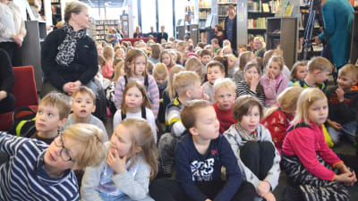 Barn på plats i Borgå stadsbibliotek för att höra vem som vann Runeberg juniorpriset.