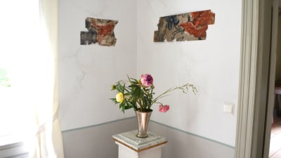 Bitar av 1700-tals tapet har hängts upp på väggen som konst.