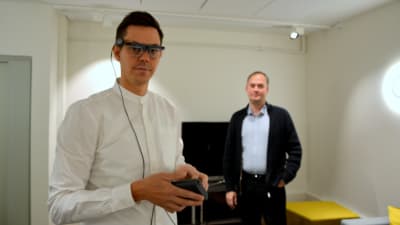Utvecklaren Joachim Majors visar glasögonen som mäter ögonrörelser. Verksamhetschefen Kimmo Rautanen står i bakgrunden.