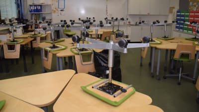 Stolar är upp och ner på pulpeter i ett klassrum.