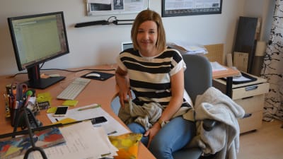 Sofia Sundholm framför hennes skrivbord vid SÖUs kontor iklädd randig t-skjorta.