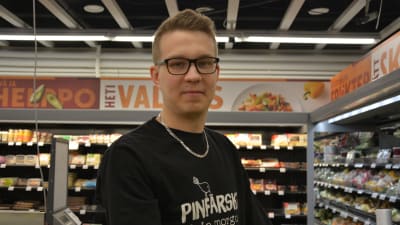 Fredrik Lönnqvist står i en livsmedelsbutik och tittar in i kameran.