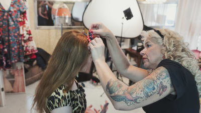 Anita Hallapelto knyter en rosett i programledaren Hannamari Hoikkalas hår. 