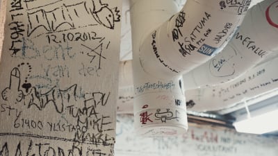 Vita väggar och ventilationsrör täckta med graffiti och texter skrivna med tuschpenna.