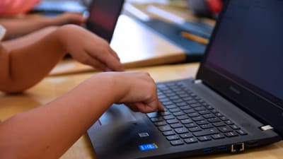 Barn händer som skriver på datorn