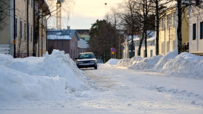 Plogad gata med höga snödrivor.