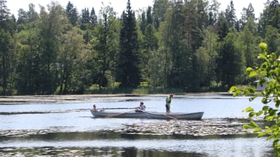 två stadsroddbåtar ute på sjön i Gallträsk. två personer sitter i en båt och en person står i en annan.