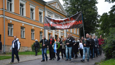 Demonstranter marscherar och bär en banderoll.