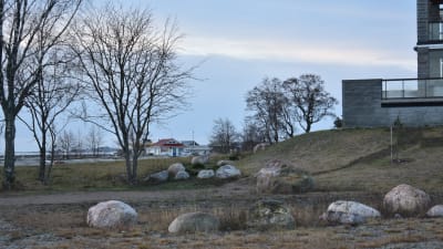 En gräsplan och stenar vid ett vitt flervåningshus.