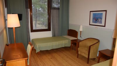 Rum med sängar, bord, fotölj och stol