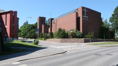 Vägkorsning i Övre Malm i Helsingfors. I bakgrunden finns en kyrka med ett stort kors på väggen.