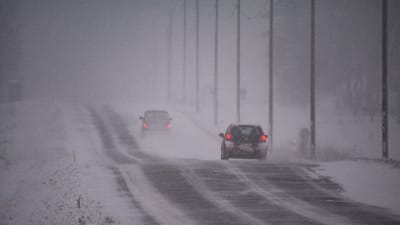 Två bilar kör längs landsväg i snöstorm