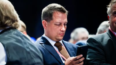 Vilhelm Junnila ser ner på sin telefonskärm.