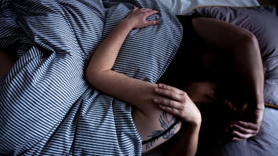 Två människor ligger under täcket i en säng. De håller om varandra medan de sover.