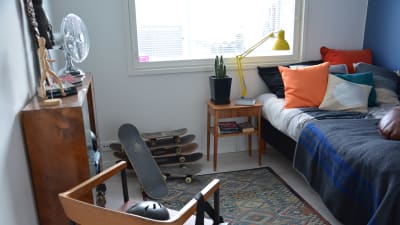 ett rum inrett med enbart begagnade prylar. skateboards, fläkt, en gul lampa och en gammal matta finns till exempel i rummet.