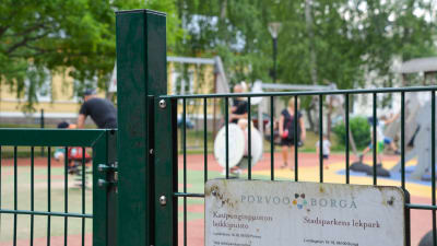 Muminparken i Borgå stadsparken. I bilden syns parkens gröna staket och i bakgrunden barn som leker. 