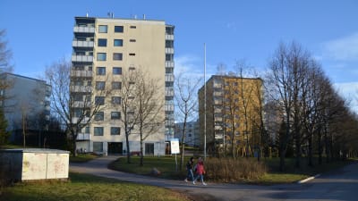 Två barn går framför två höghus