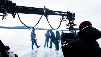 En grupp människor står på isen medan några andra filmar dem.