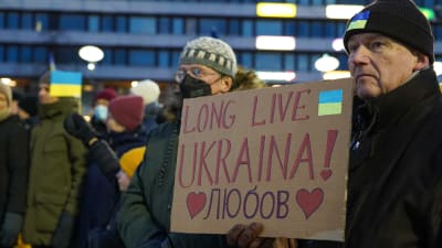 En man håller upp en skylt i paff med texten "länge leve Ukraina" på engelska.