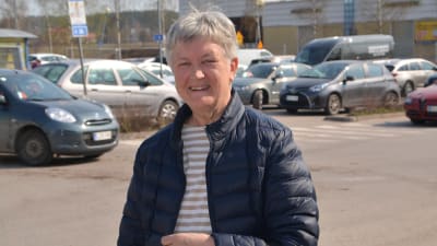 Kvinna står på en parkering och ler