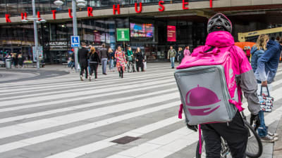 Foodora-bud står utanför Kulturhuset i Stockholm med sin cykel.