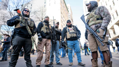 En grupp med män står på gatan med tunga vapen.