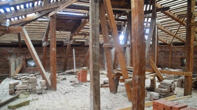 Vindsvåning med stadiga träbjälkar i ett stenhus som renoveras, byggarbetsplats.