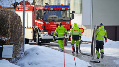 Män bär på rör och går mot brandbil