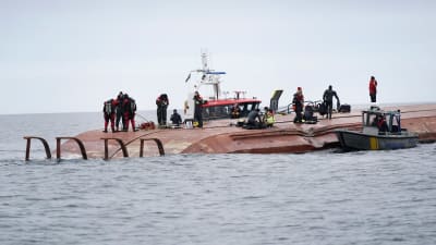Dykare och andra räddningsarbetare står på det kapsejsade fartyget Karin Hoej.