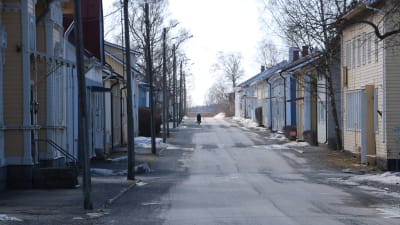 En gata i Kaskö med trähus på båda sidorna. En ensam cyklist skymtar fram på vägen.