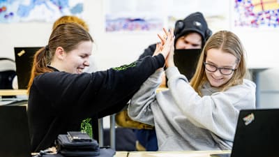 Två elever gör high five med båda händerna.