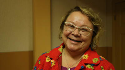En kvinna med färggrann tröja ler.