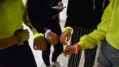 Ungdomar på skoldisko visar fram neonlysande armband