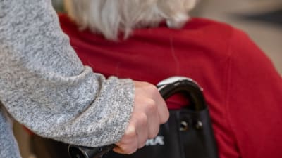 Äldre person skuffas i rullstol