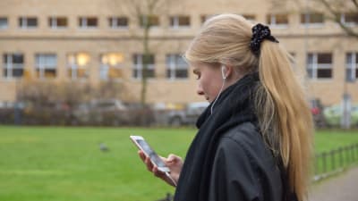 Hanna Ylöstalo lyssnar på ljudbok via sina hörlurar.