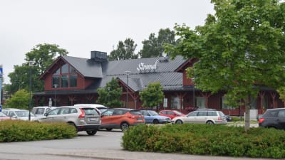 Köpcentret Strand i Ingå. Framför byggnaden står bilar parkerade på en parkering.