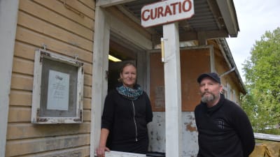 Kvinna och man på trappan till ett gammalt trähus.