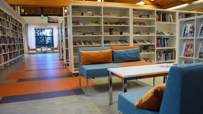 Korridor i ett bibliotek med soffor och bord.