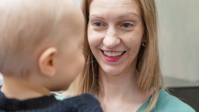 Noora Forsbom hymyilee sylissään olevalle lapselleen. 