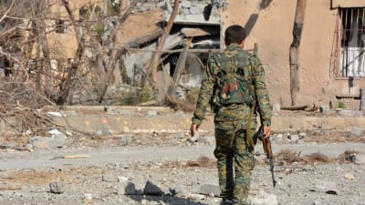 En YPG-krigare går längs med en förstörd gata i terrorgruppen IS tidigare syriska huvudstad Raqqa.